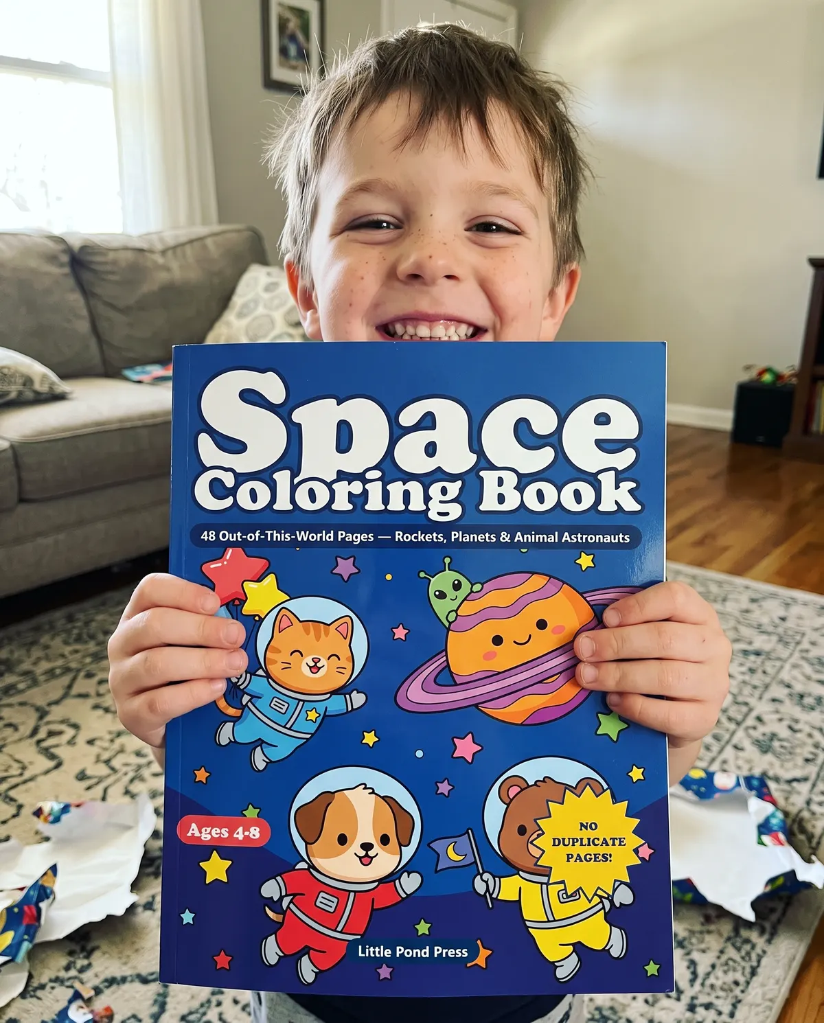 A boy holding up the Space coloring book with both hands